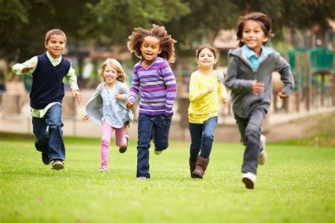 Group Of Young Children Running Towards Camera In Park - QUILS