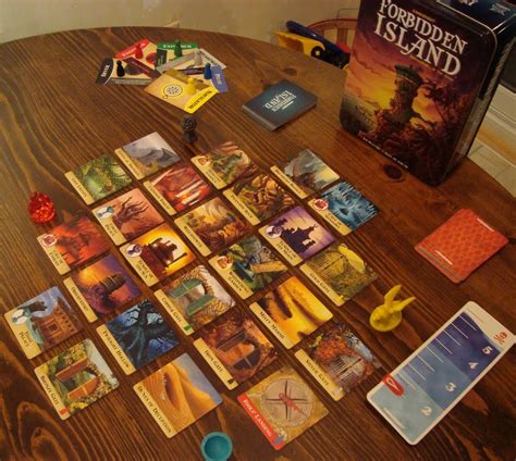 the board game forbidden island is set up on a table next to an open book
