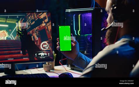 Man watching tutorial on green screen phone while playing first person ...