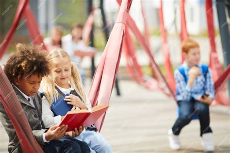 Premium Photo | School children reading books outdoors