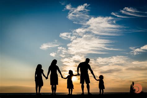 A family hold hands creating a lovely silhouette against the sunset ...