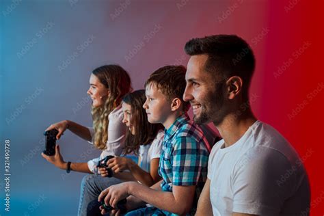 Father, mother and children playing a video game at modern gaming club ...
