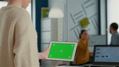 Woman holding tablet with green screen mockup display standing in busy ...