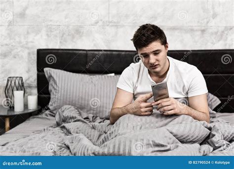 Young Tired Man Looking at His Mobile Phone while Sitting in Sty Stock ...