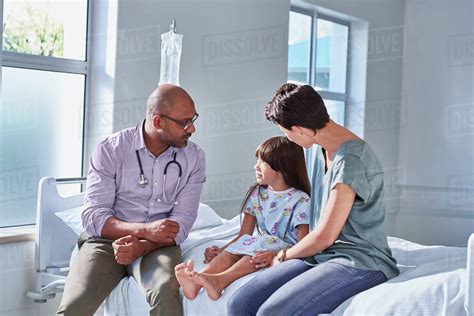 Male doctor talking to girl patient and her mother in hospital children ...