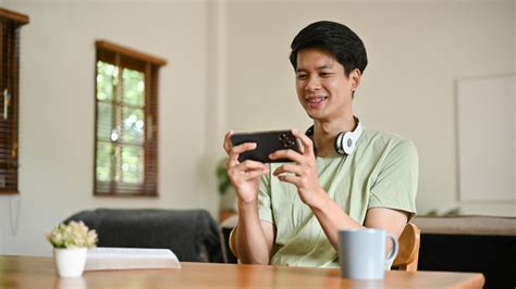 Premium Photo | A cheerful asian man enjoys playing mobile games on his ...
