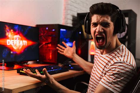 Side view of Angry gamer playing video games on computer Stock Photo ...