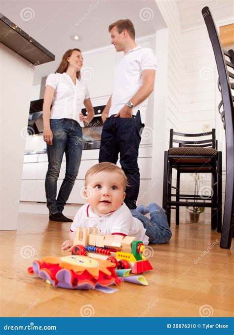 Baby Playing on Floor with Parents in Background Stock Photo - Image of ...