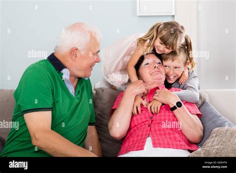 Elderly Grandparent Playing With Grandchildren On Couch Together At ...