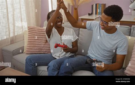 Mother and son high-fiving while playing video games at home on a cozy ...